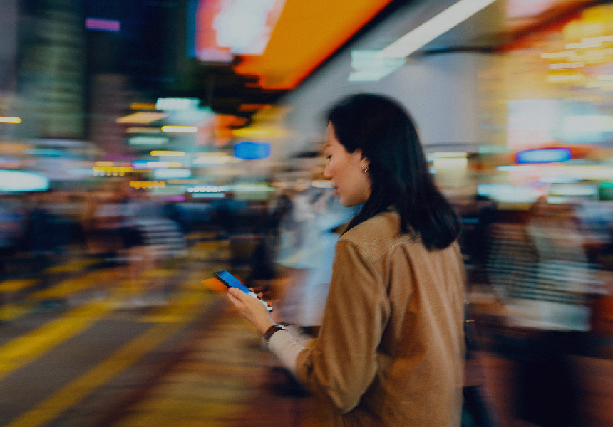 Mulher a olhar para o telemóvel na mão com um fundo rápido